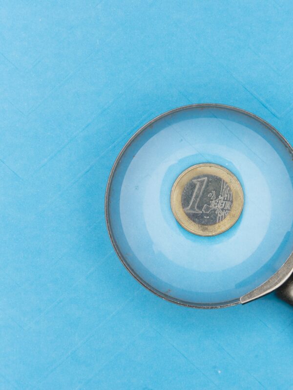 une loupe regarde une pièce de & euro posée sur un fond bleu